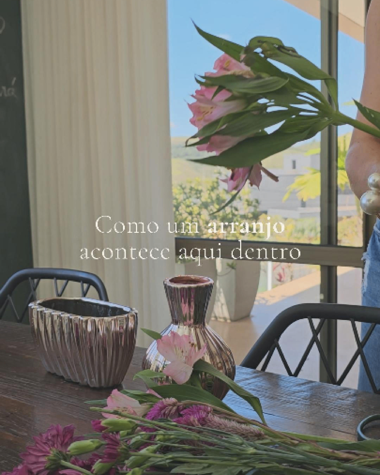 Bastidor do ateliê com vasos, flores e vista para a serra.