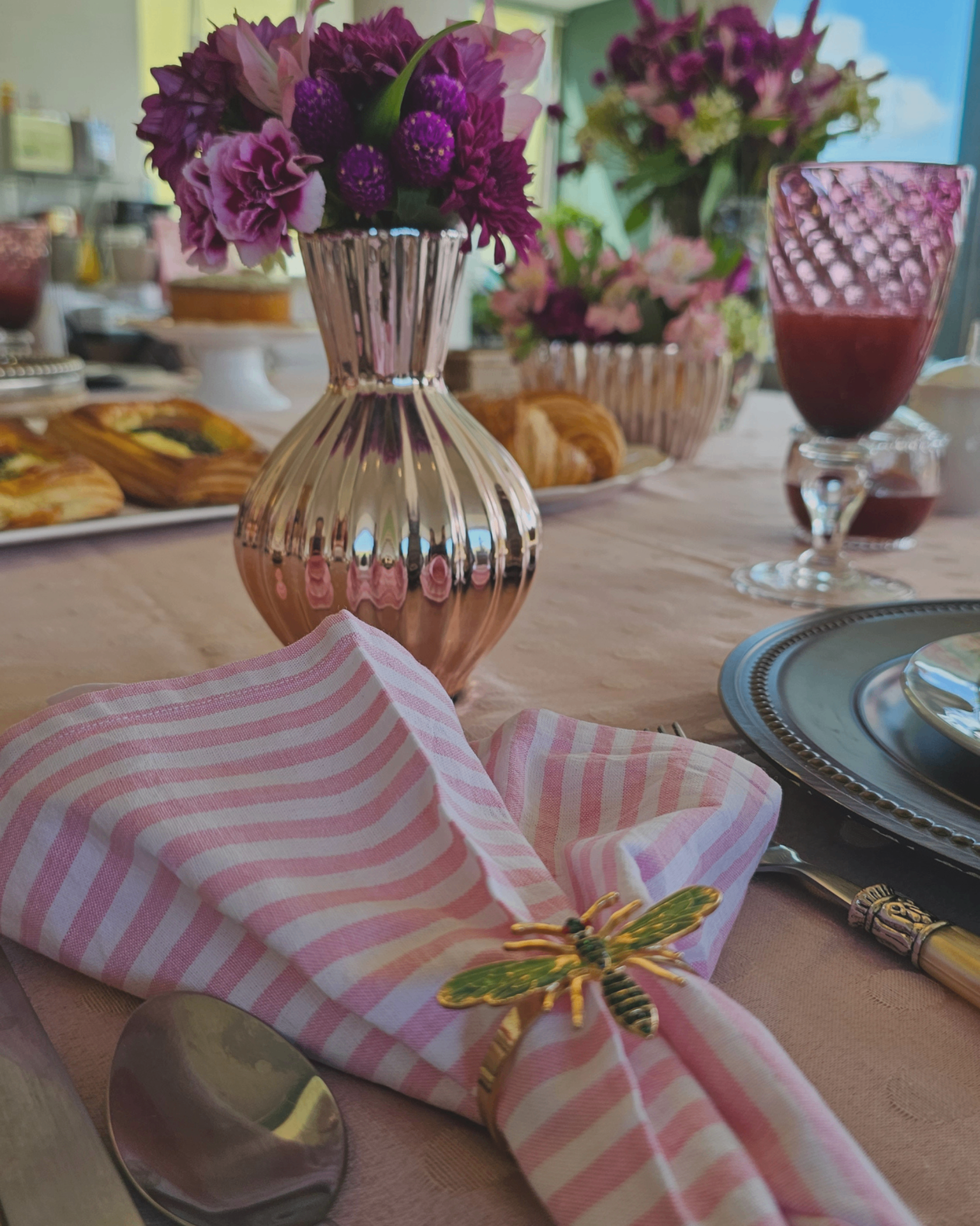 Mesa de café com guardanapo listrado rosa e vaso perolado com flores.