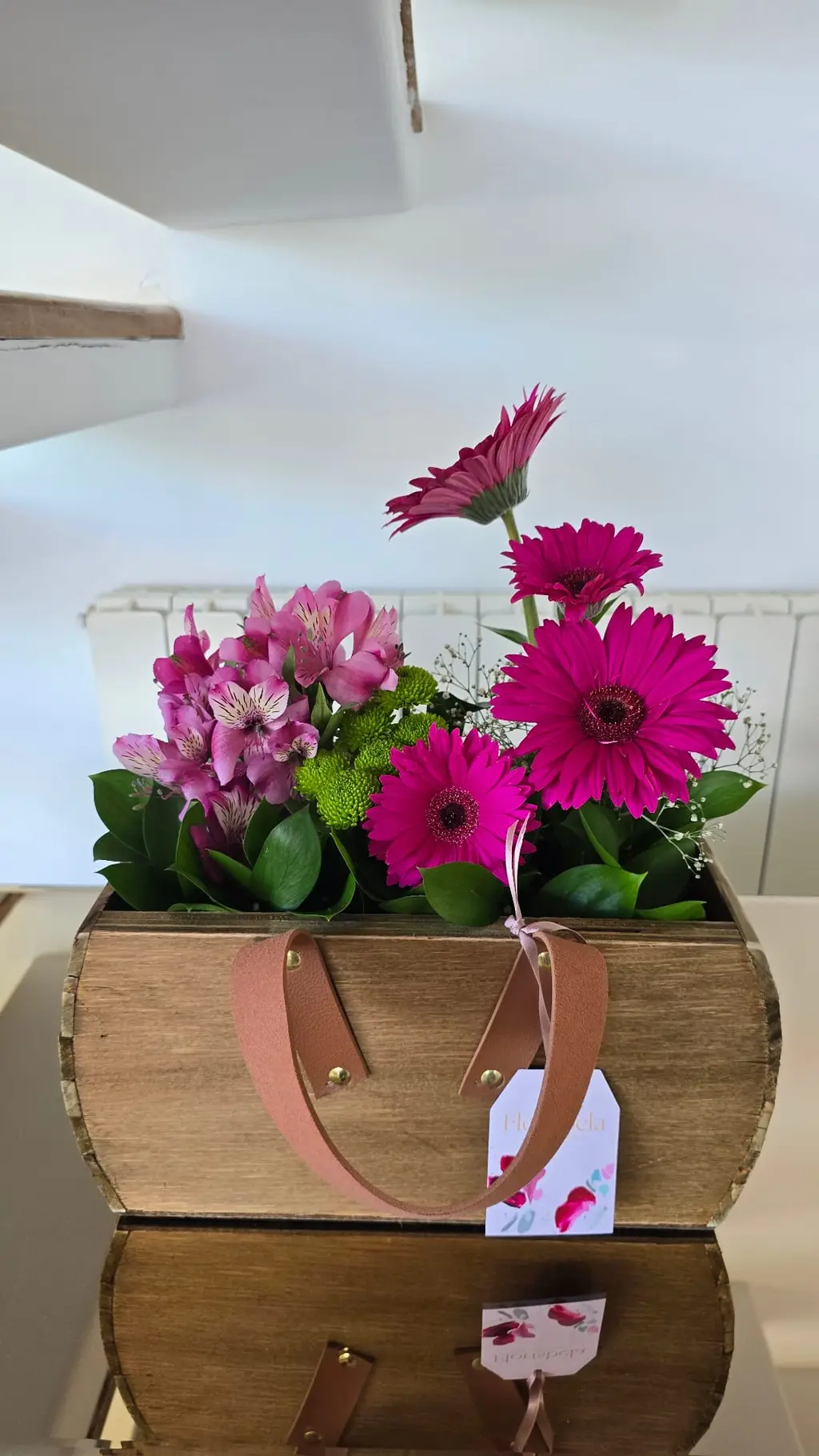 Arranjo de mesa em caixote de madeira com gérberas magenta e alstromérias rosa.