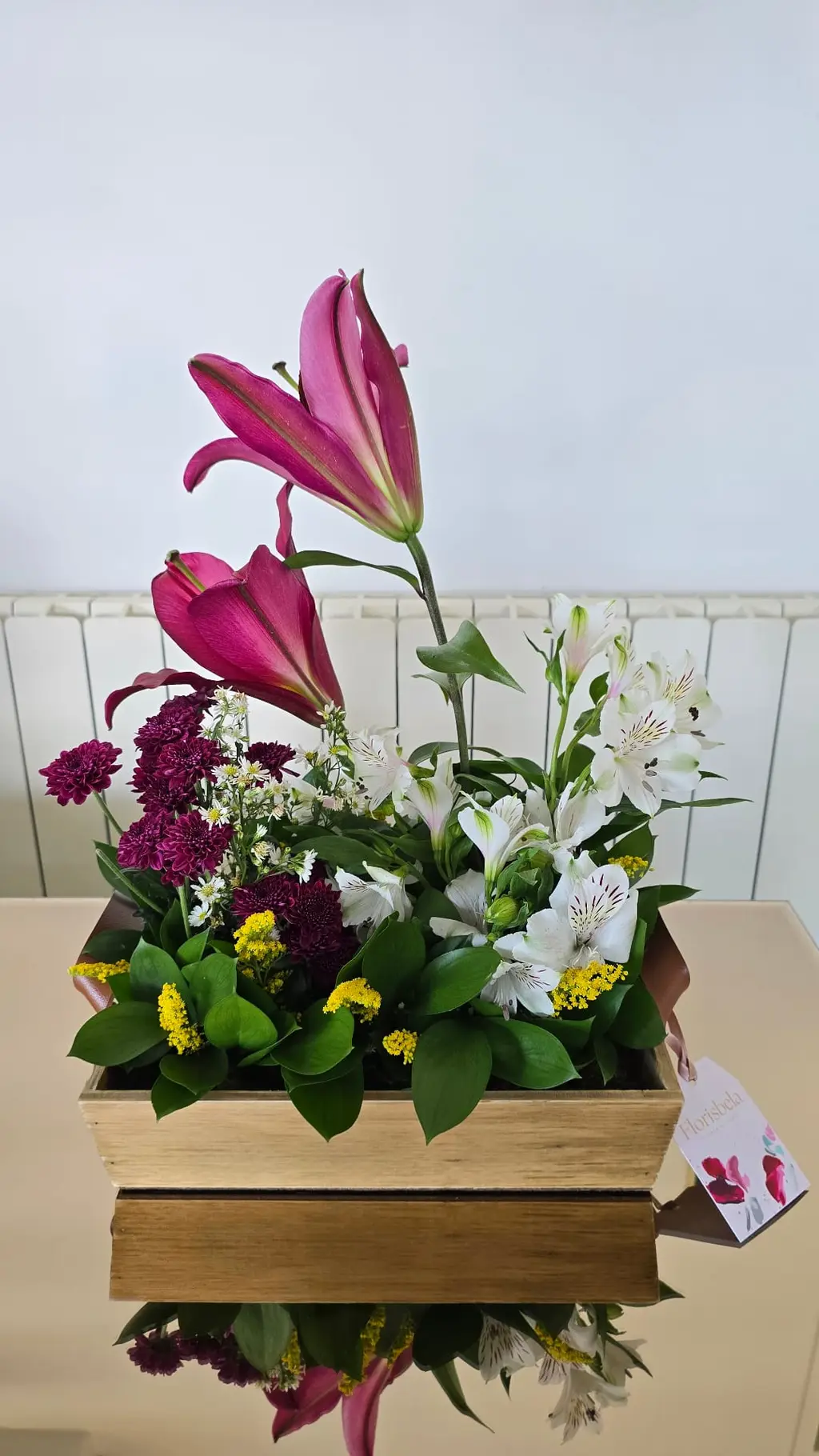 Arranjo alto em caixote de madeira com lírios magenta, alstromérias brancas e mini margaridas.