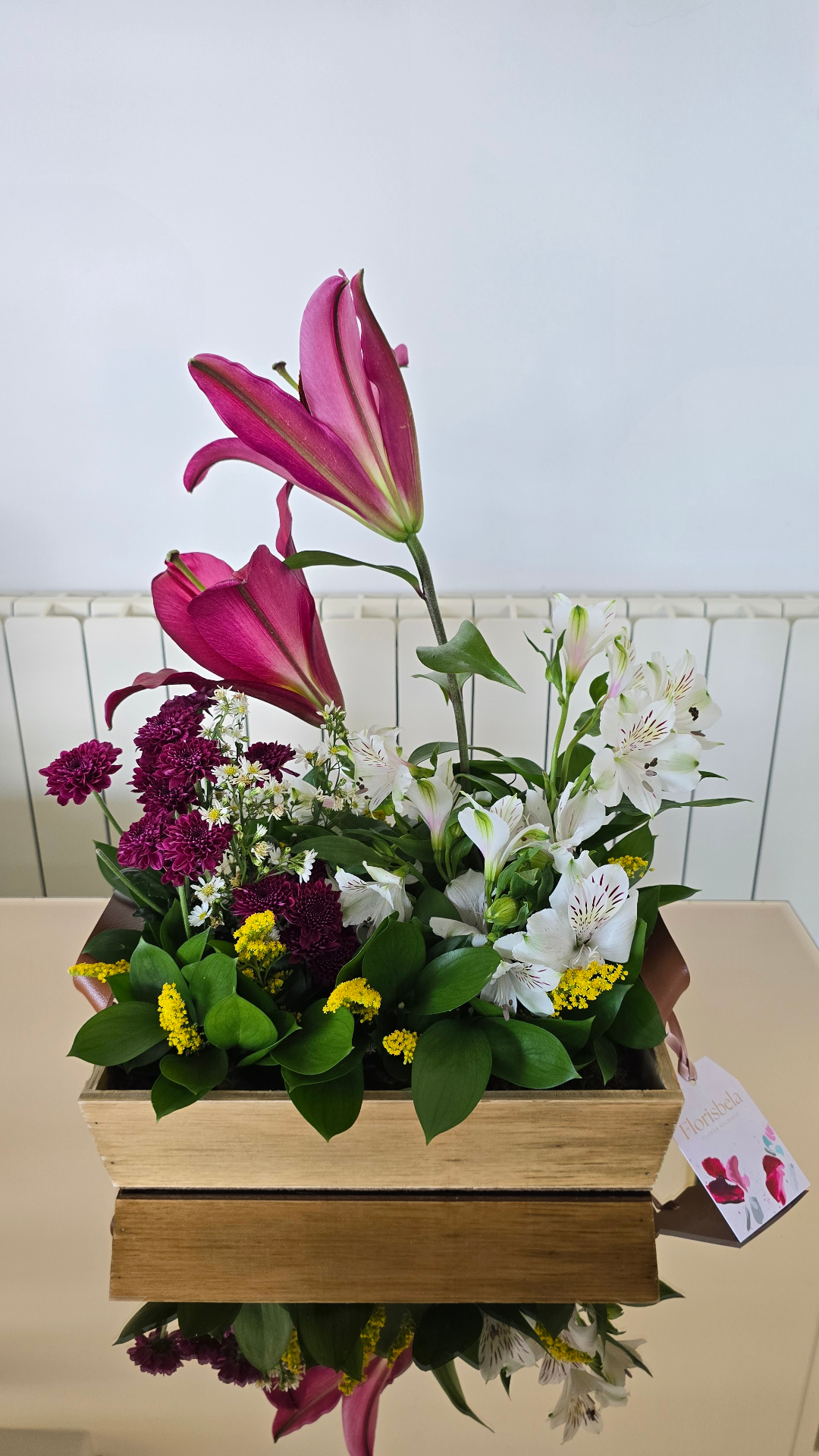Arranjo alto em caixote de madeira com lírios magenta, alstromérias brancas e mini margaridas.