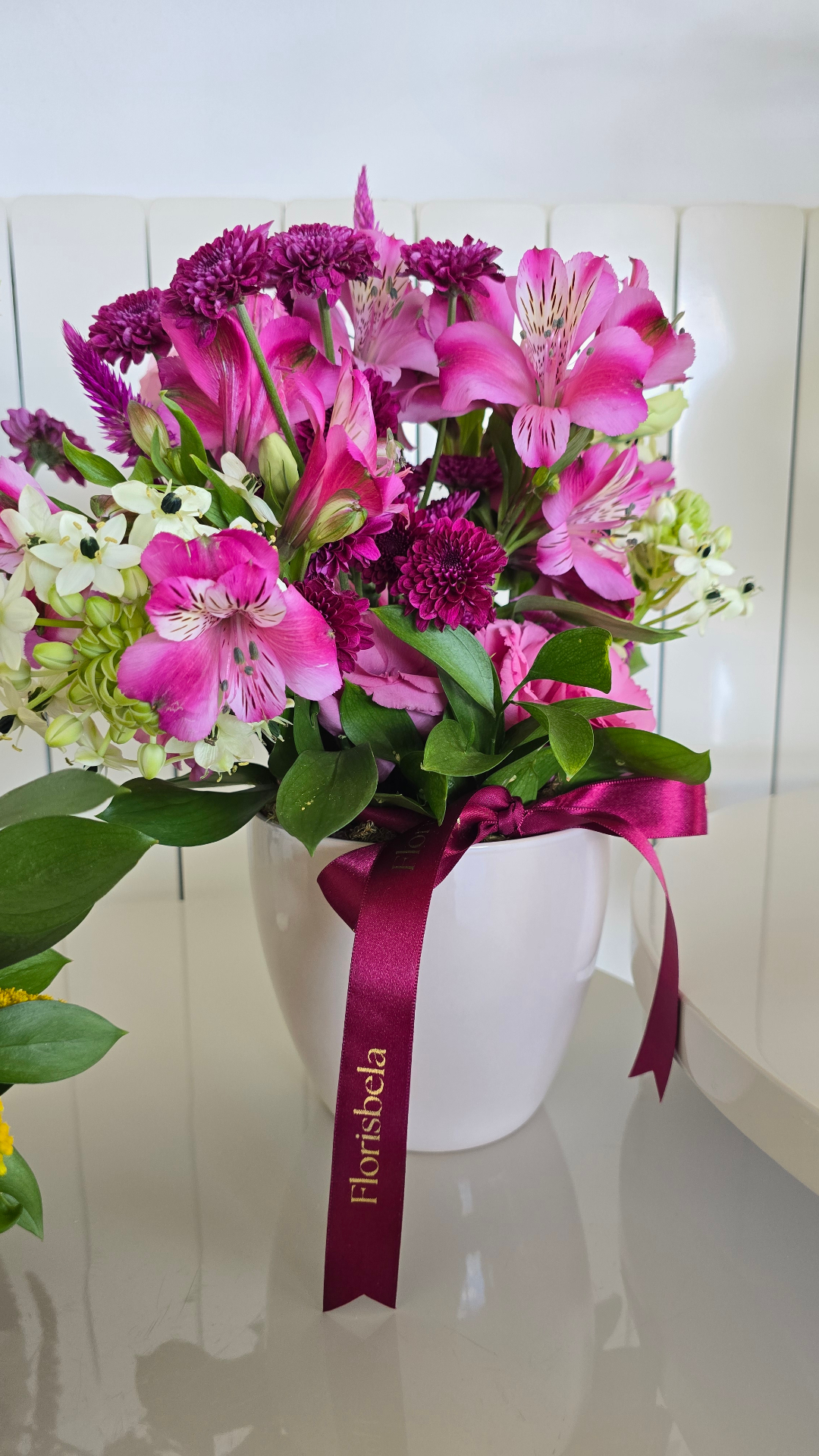 Arranjo de mesa magenta e rosa em vaso branco com fita Florisbela.
